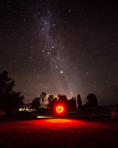 Night sky with illuminated red heart on the ground