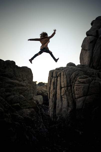 Person leaping between two boulders in a mountain