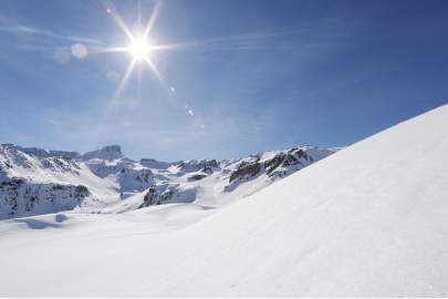 Snow covered mountains with the bright sun shining in the sky