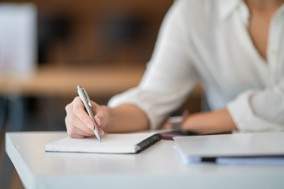 A woman sitting at a desk writing in a notebook