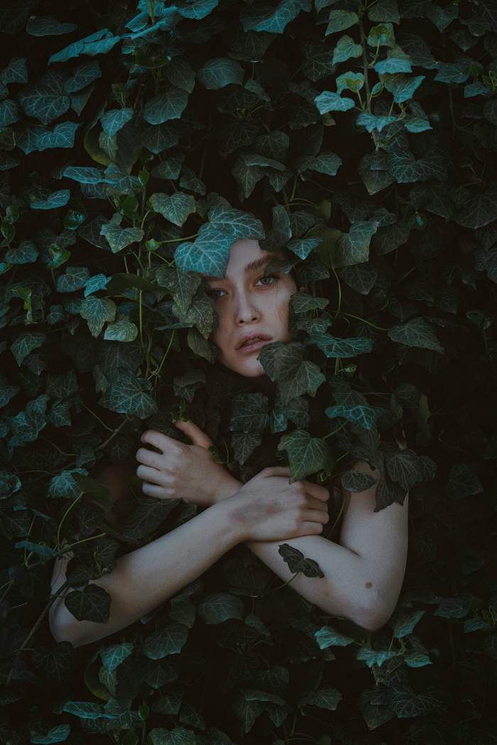 Woman hidden behind green vines