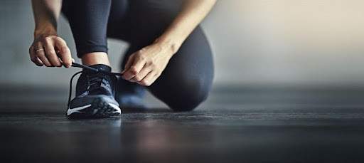 Woman in workout clothes bending down to tie her shoes