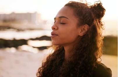 Young girl with long curly hair with eyes closed meditating