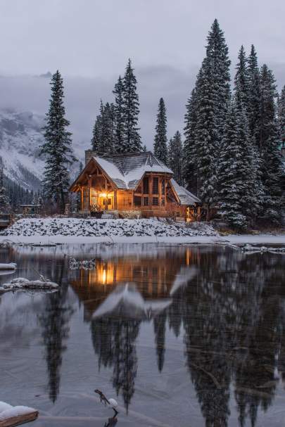 cabin in the woods surrounded by snow capped mountains and cypress trees