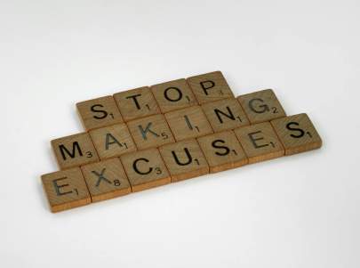 scrabble wooden letters that spell stop making excuses